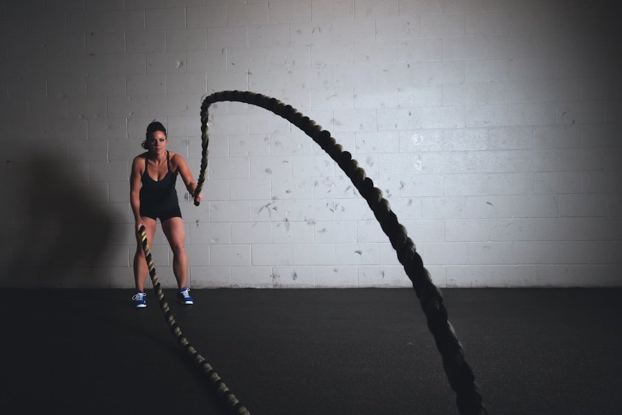 Young woman doing a rope-workout inside a gym