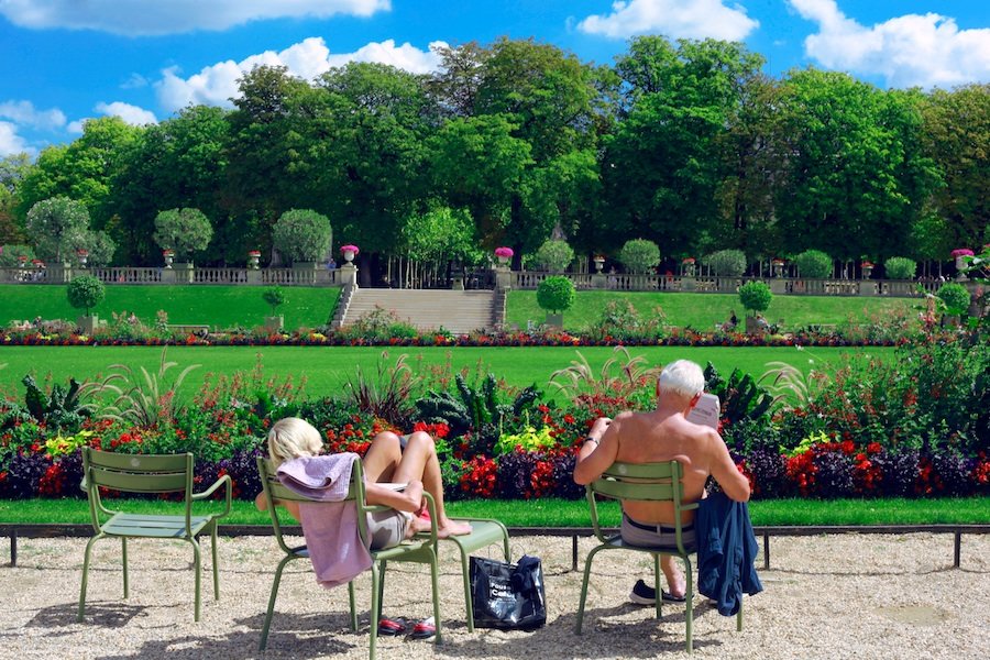 Elderly man and woman reading newspapers while bathing in the sun