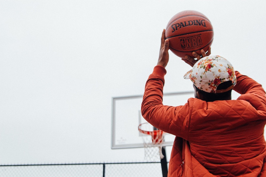 Young man taking a basketball shot at his home court 