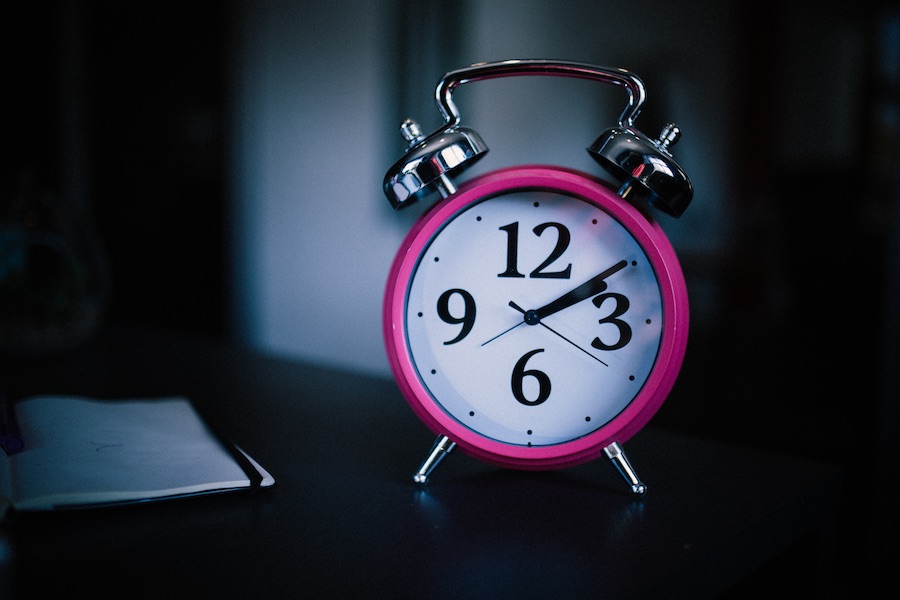 Alarm clock standing on the night stand inside the bedroom