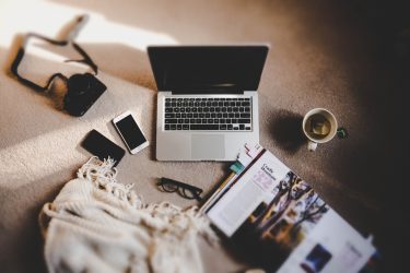 laptop laying on the carpet with coffee and cellphone nearby
