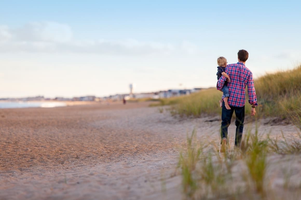 Dad holding his son while walking on the beach