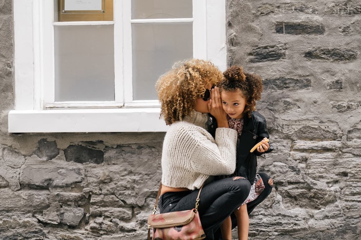 Mother whispering a secret to her daughter