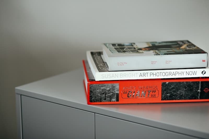 Three books stacked on top of each other on a grey file cabinet