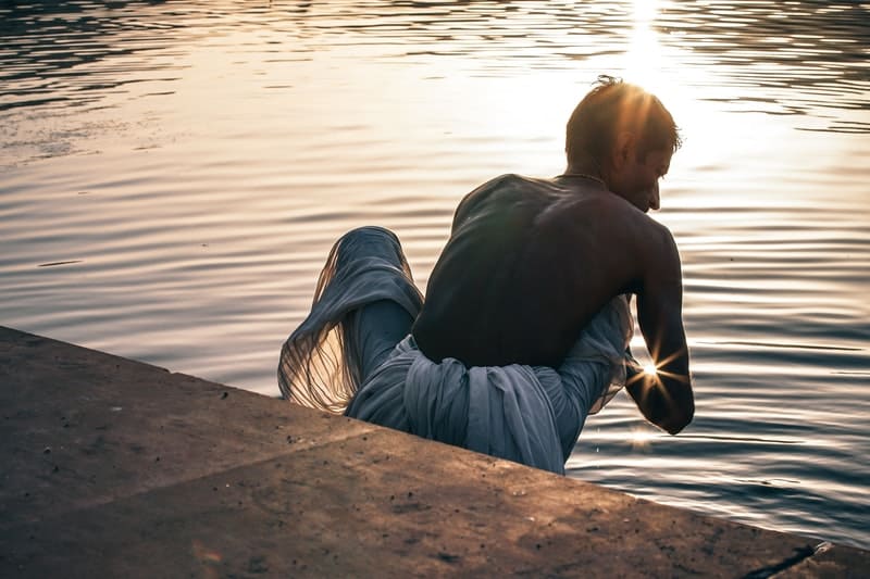 holy indian man bathing in a holy lake during sunrise