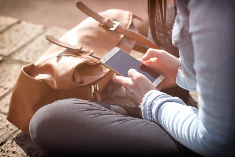 Young woman holding her smartphone while sitting