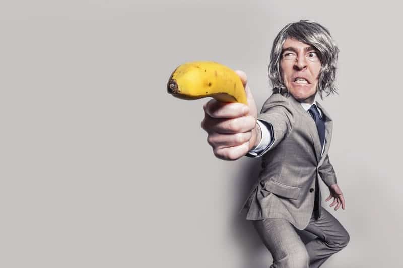 man-in-gray-suit-jacket-holding-yellow-banana-fruit-while-making-face