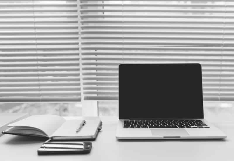 Notebook laptop and a smartphone laying together on top of a workspace desk