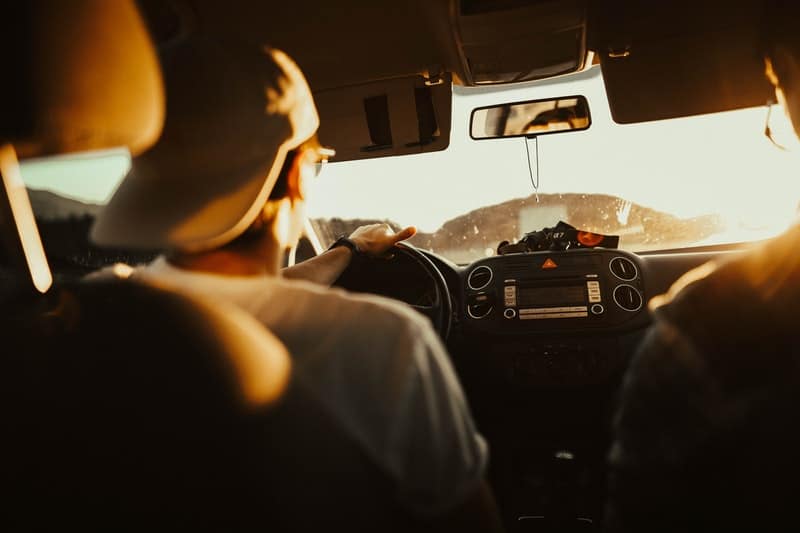 adult man driving his car back home after work during sunset