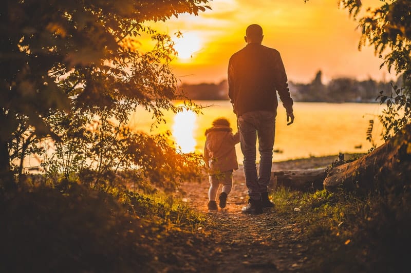 father and son walking into the sunset