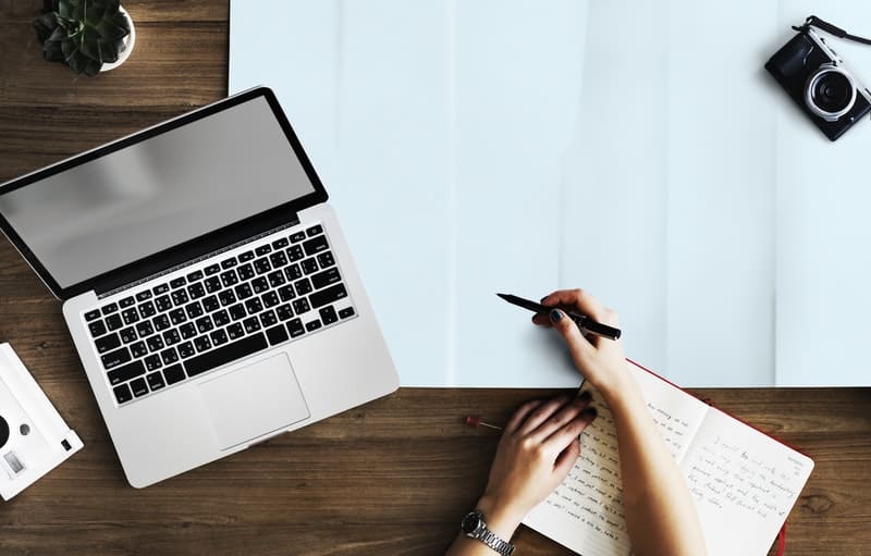 person holding pen near macbook pro