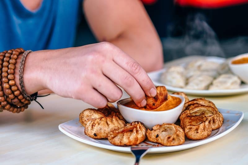 Man dipping a fried momo into delicious sauce in kathmandu nepal