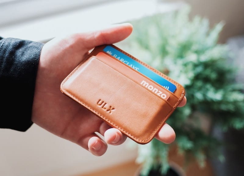 Man holding a classy leather wallet with credit cards inside