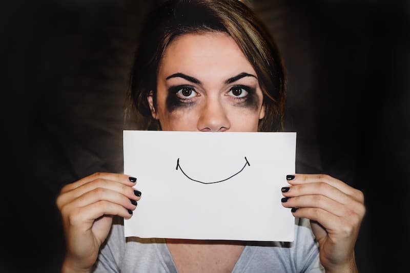 Unhappy Woman Holding up a Drawing of a Smile Face