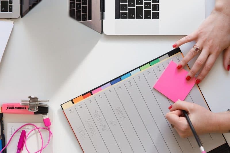 Woman writing on a pink sticky note