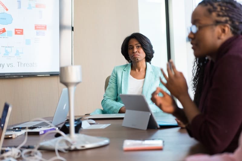 business woman listening to a powerpoint presentation by a coworker