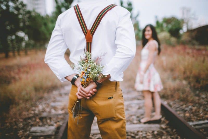 man holding bouquet of flowers for his woman