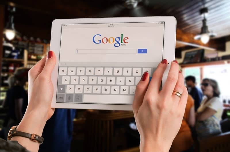 person holding an ipad with google homepage