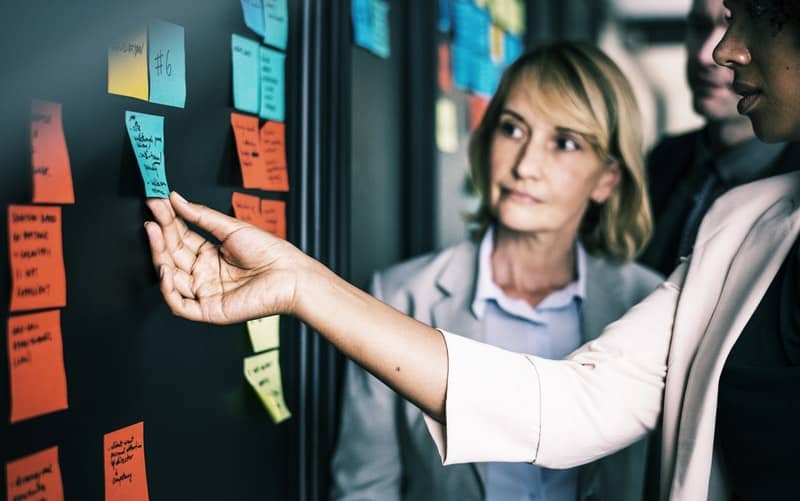 womna holding sticky notes at a business meeting