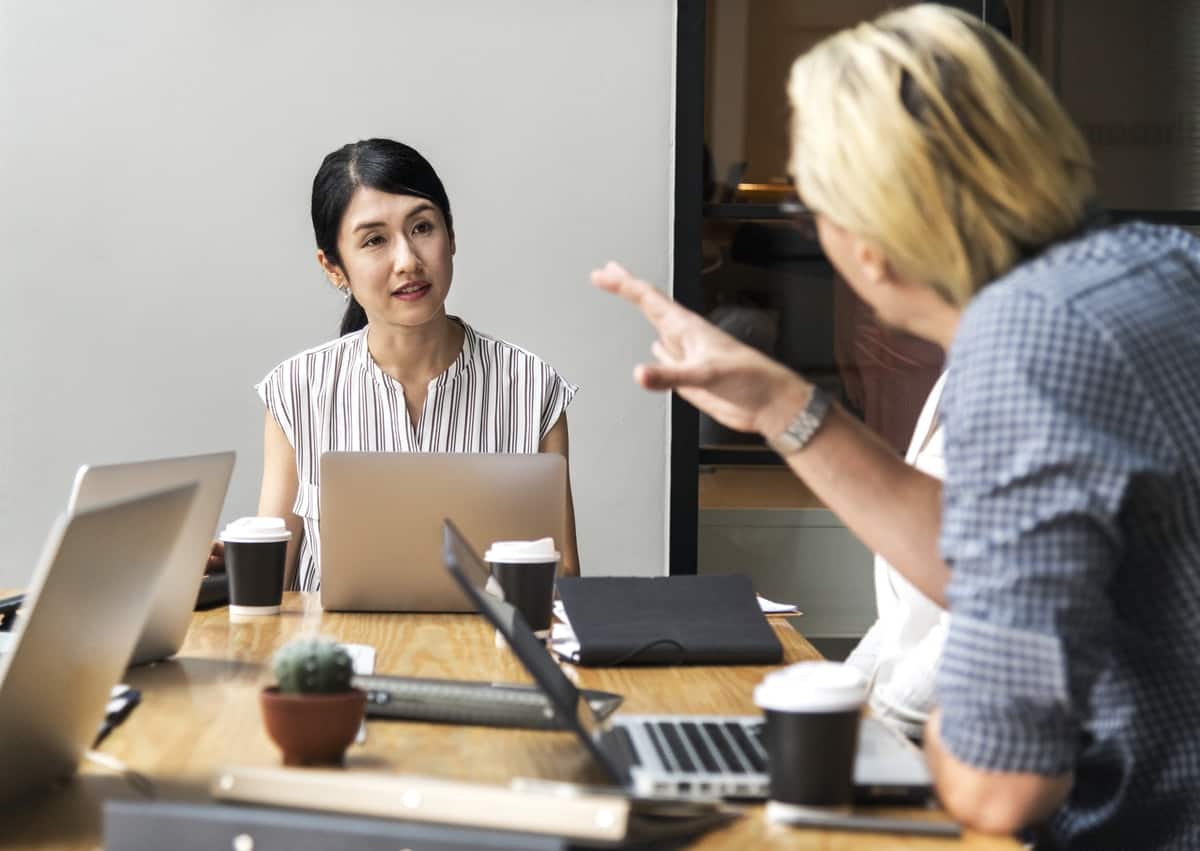 Man Talking to a Woman Sitting in Front of Silver Laptop Computer