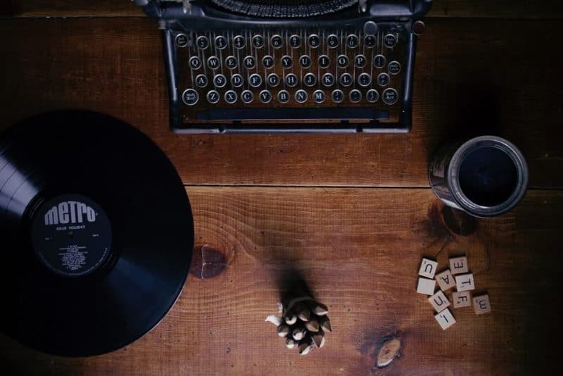 Scrabble pieces laying next to a vintage typewriter