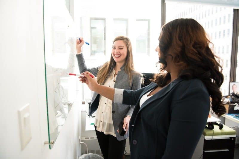 Two Women Writing on Dry Erase Board