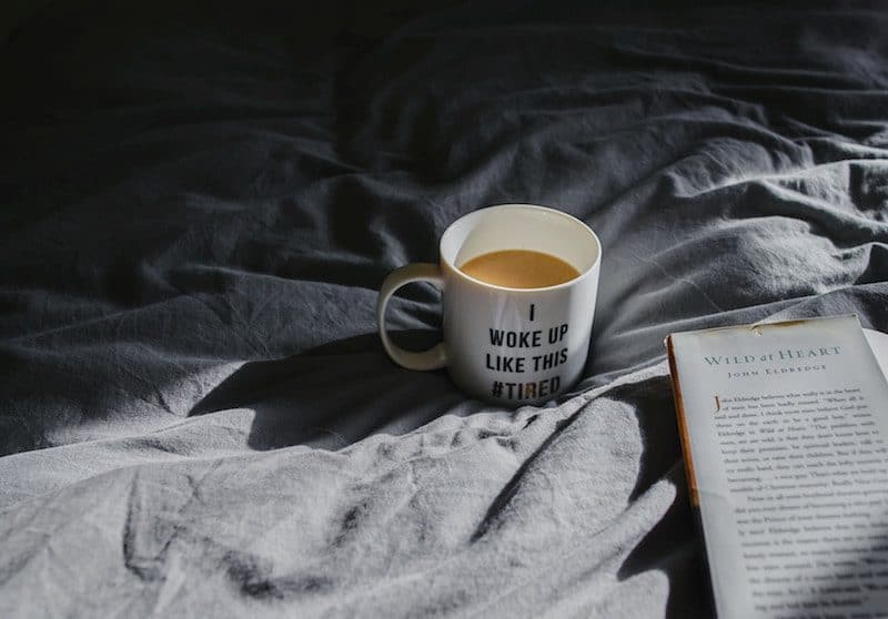 coffee and a book laying on top of a comfy mattress