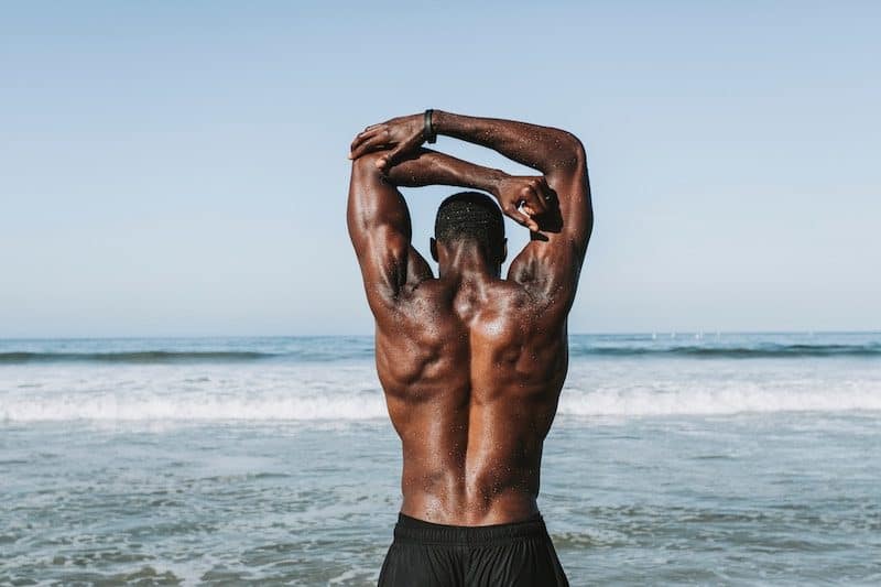 man at the beach stretching his arms