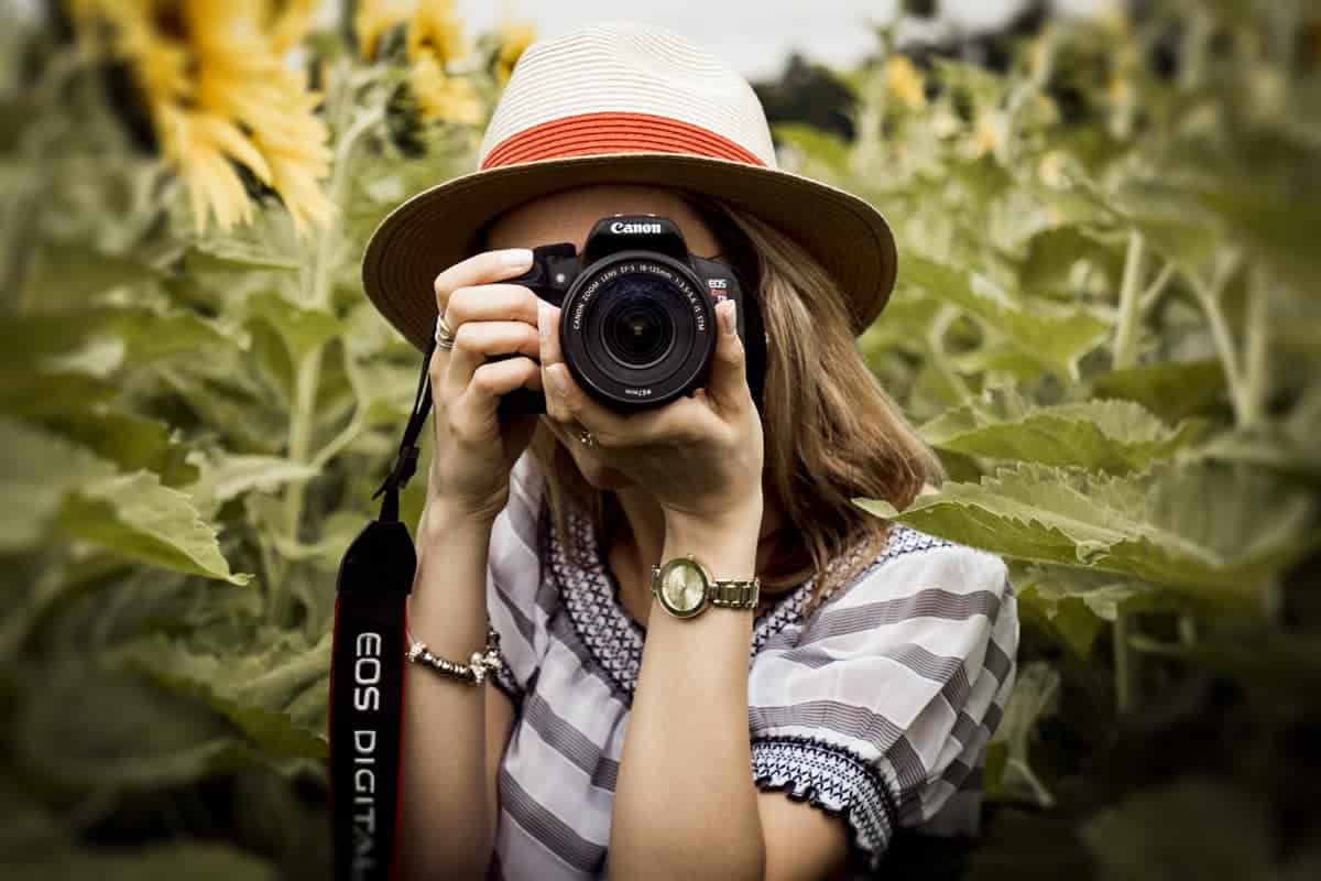 woman holding a DSLR camera in a sunflower field