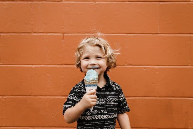Cute Kid eating ice cream against an orange background