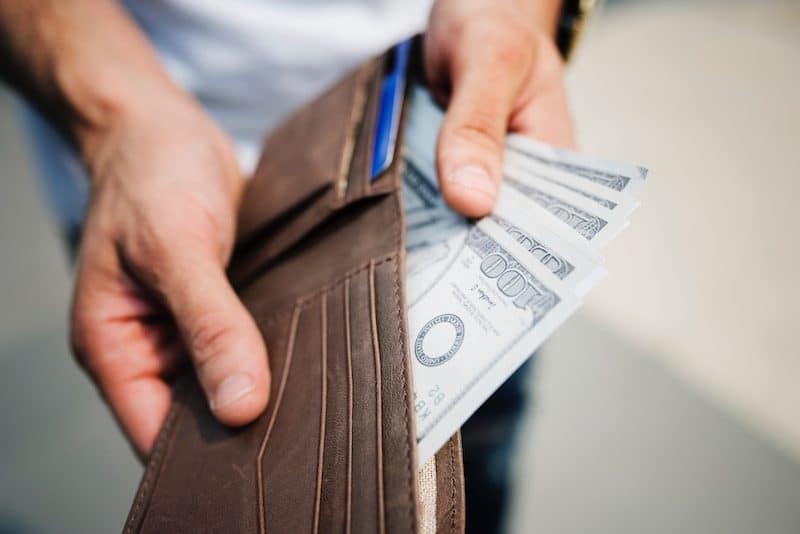 Man Pulling 100 dollar bills out of his wallet