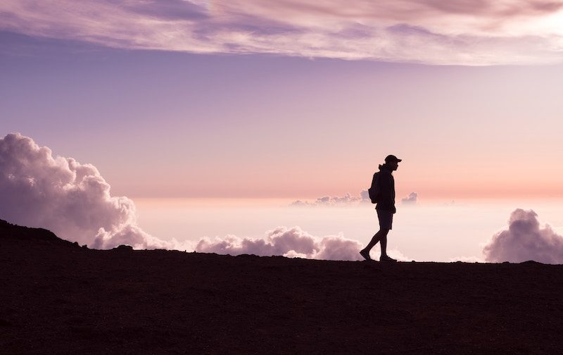 Man Walking on top of a mountain during sunset