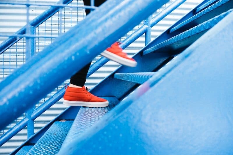 Woman with red shoes going up blue stairs