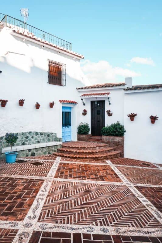 white concrete house with brown tiled yard-min