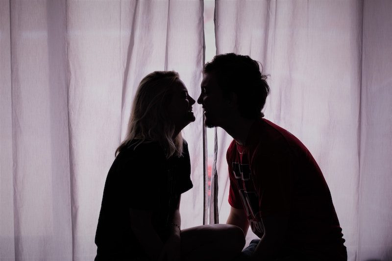 Cute couple having a sweet conversation together in front of the living room window.