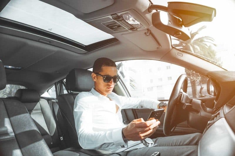 Young man nicely dressed inside a fresh car