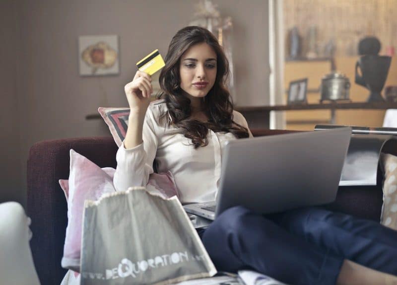 young woman holding her credit card while shopping online