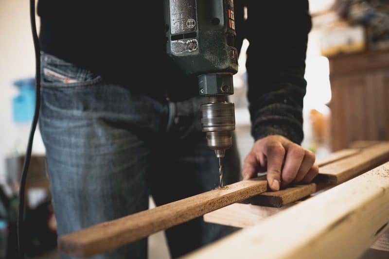 man drilling a hole in a piece of wood