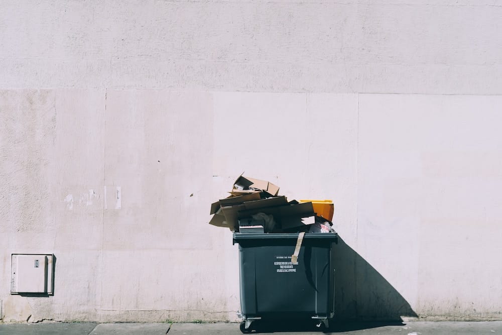 Blue Dumpster Against a White Wall