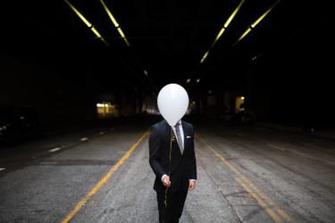 Man Hiding His Face Behind a Balloon