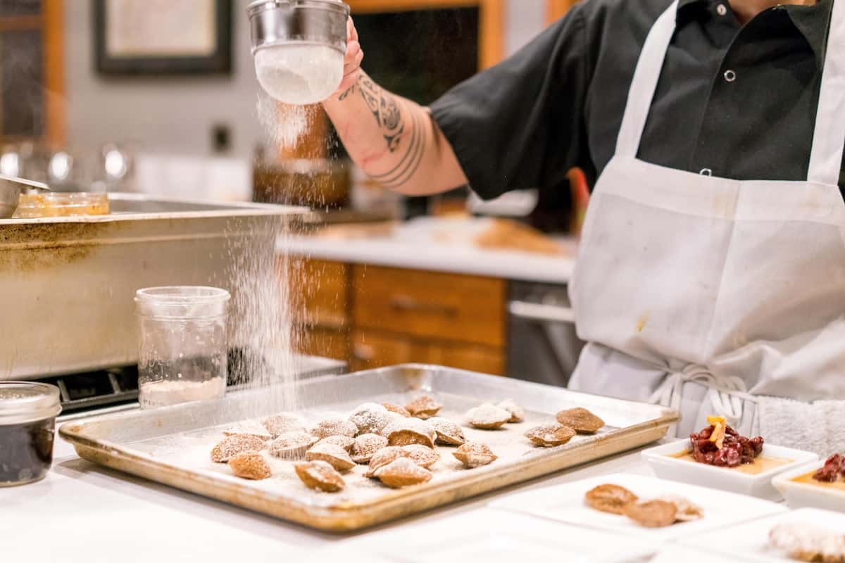 Baker adding powdered Sugar to sweets