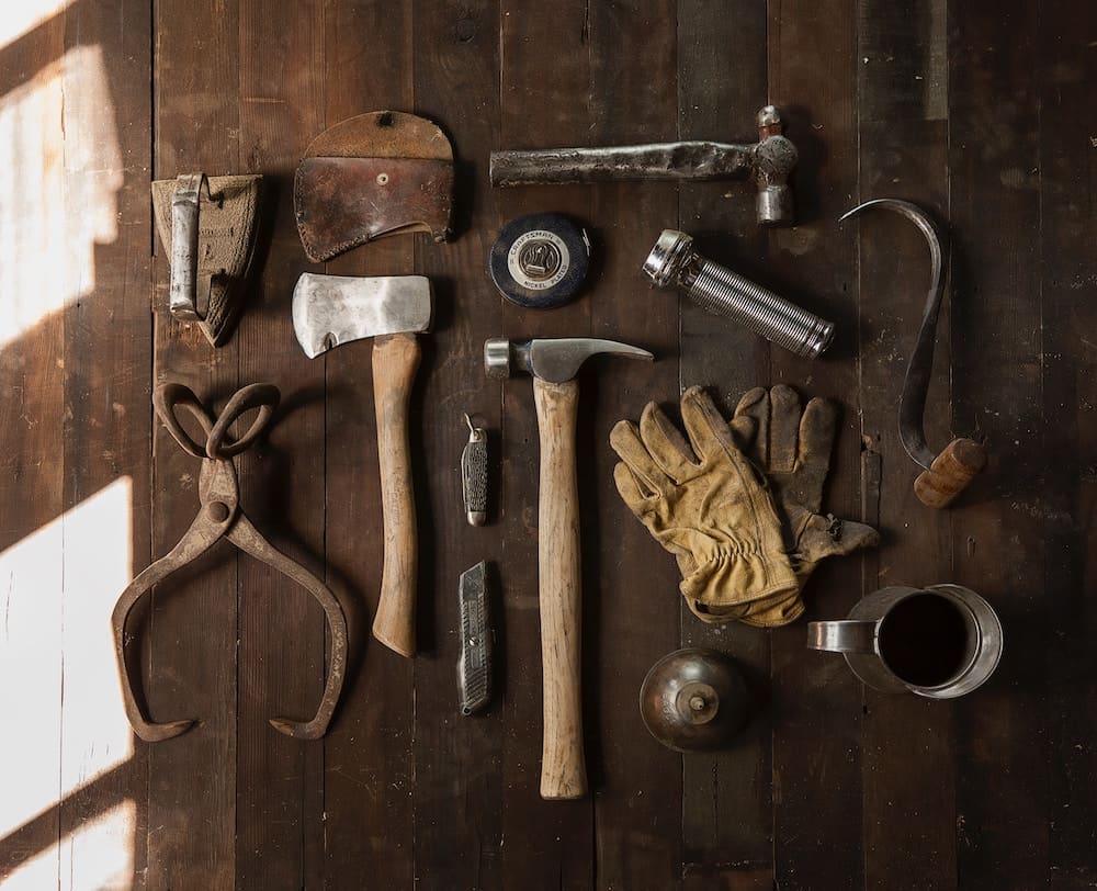 clothes iron, hammer, axe, flashlight and pitcher on brown wooden table