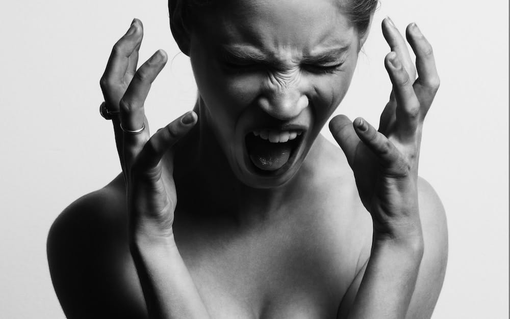 grayscale photography of woman opening her mouth while hanging her hands near her face