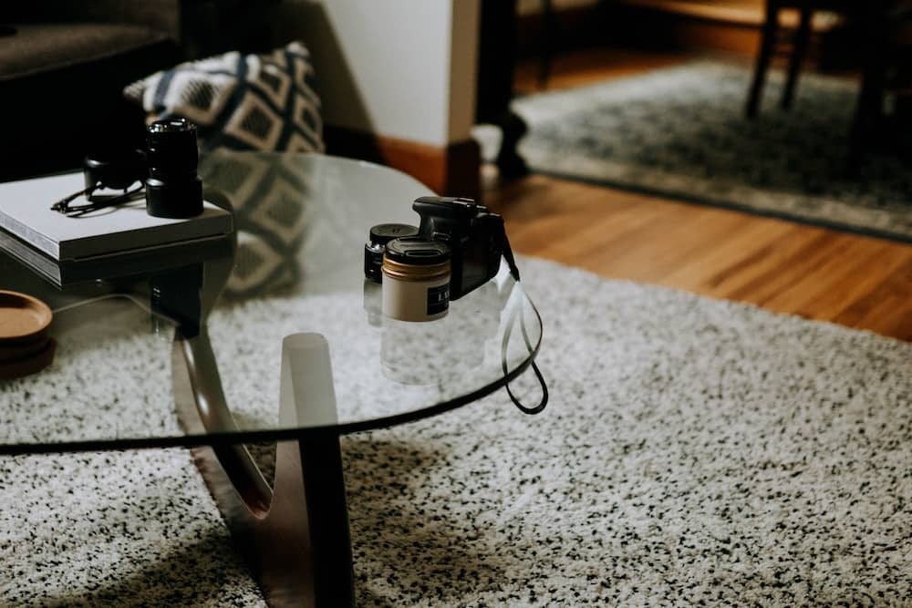 square clear glass-top coffee table on gray area rug