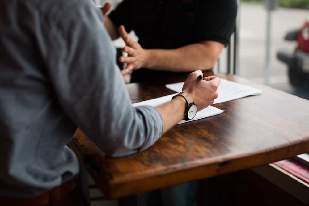 two person writing on paper on brown wooden table