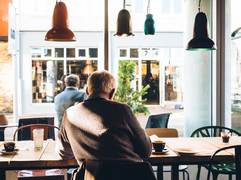 Old man sitting inside a cafe during noon