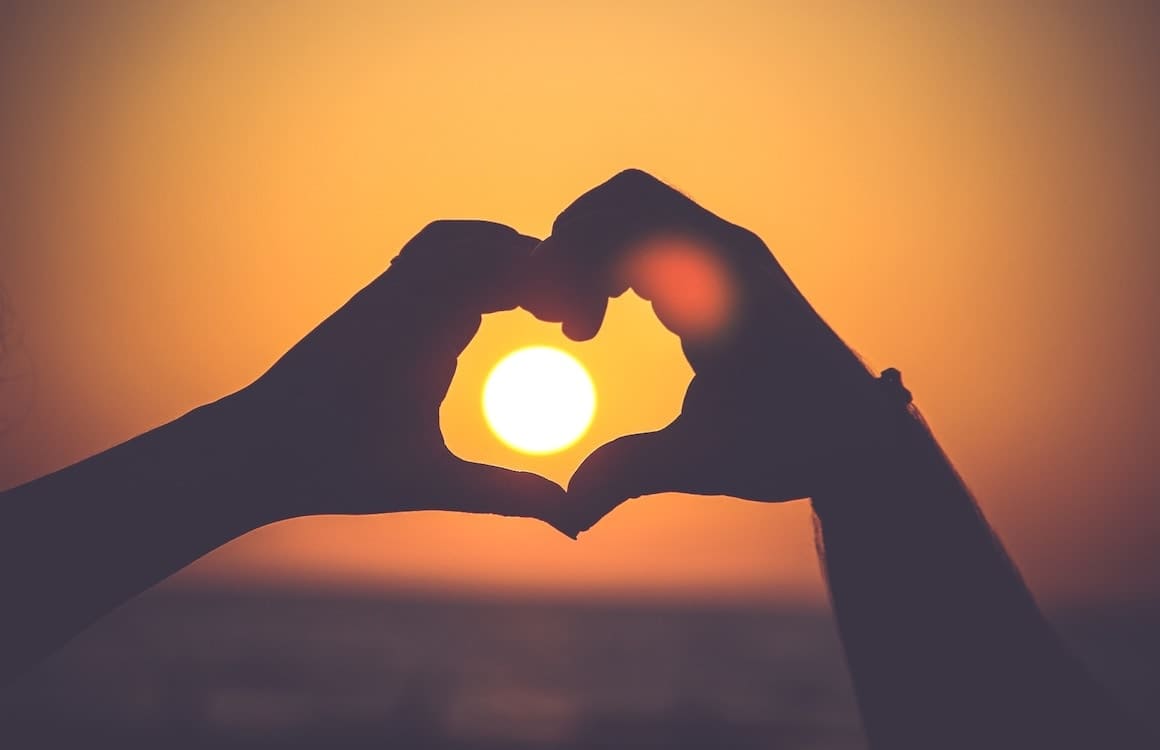 woman using her hands to create a heart shape using her hands