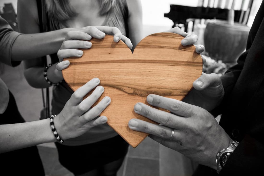 adults holding a wooden heart