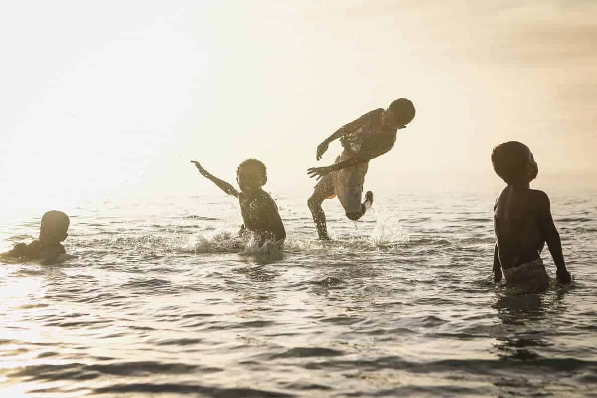 Four kids playing in the ocean during sunset