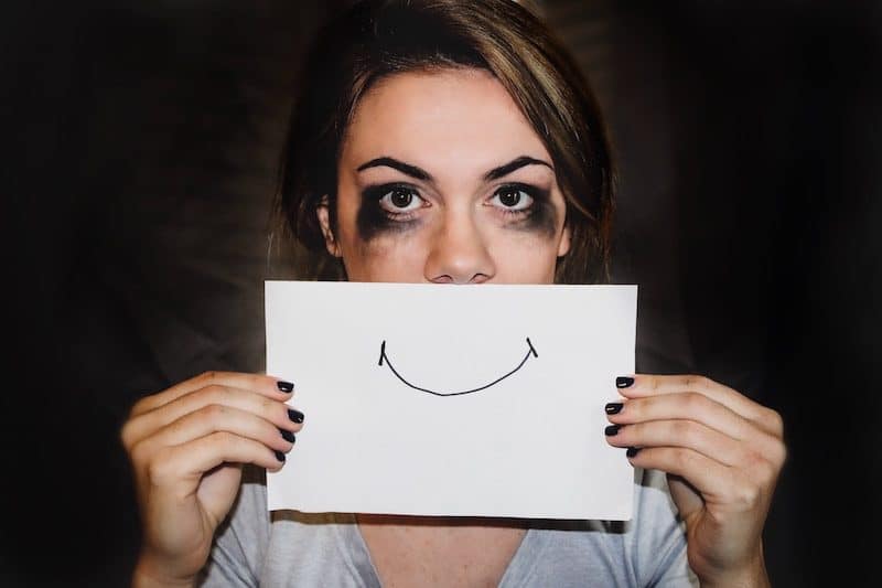 Unhappy Woman Holding up a Drawing of a Smile Face